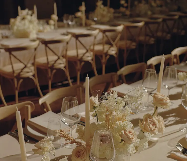 A long lunch table set with candles and roses